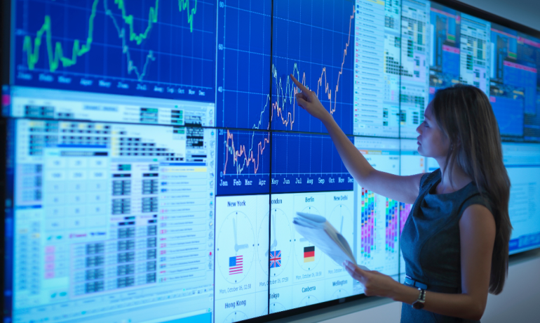 A woman looking at charts on a large screen