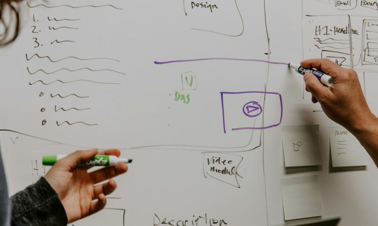 People drawing diagrams on a white board
